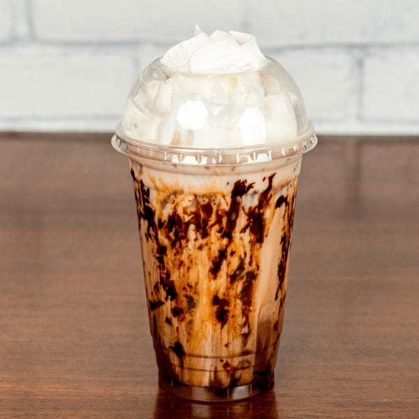 A Paradise Bakery and Cafe mocha frappe with chocolate drizzle and whipped cream in a clear cup.
